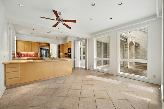 kitchen featuring kitchen peninsula, light tile patterned floors, ceiling fan, light brown cabinetry, and decorative backsplash