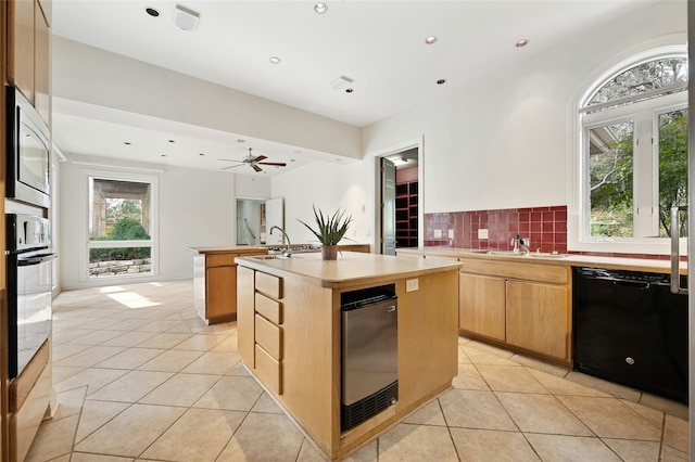 kitchen with a center island with sink, ceiling fan, black appliances, and light tile patterned floors