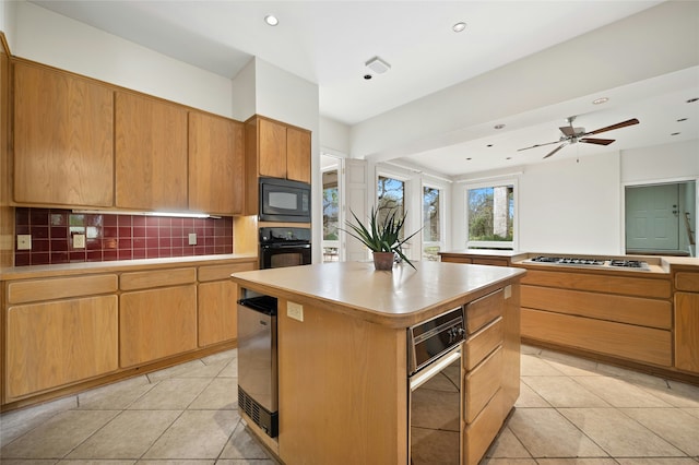 kitchen with ceiling fan, tasteful backsplash, light tile patterned floors, a kitchen island, and black appliances