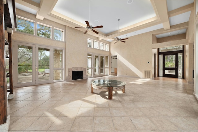 living room with a towering ceiling, light tile patterned flooring, french doors, and a healthy amount of sunlight