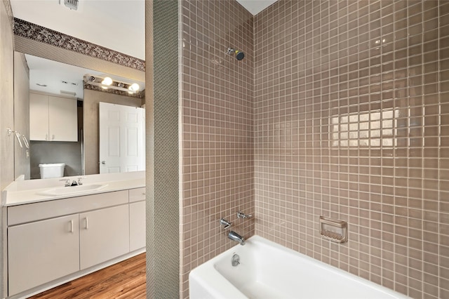 bathroom featuring wood-type flooring, vanity, and tiled shower / bath combo