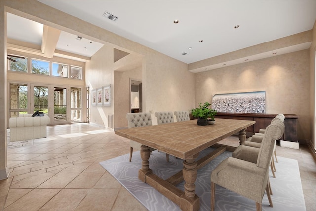 tiled dining area featuring a high ceiling and beam ceiling