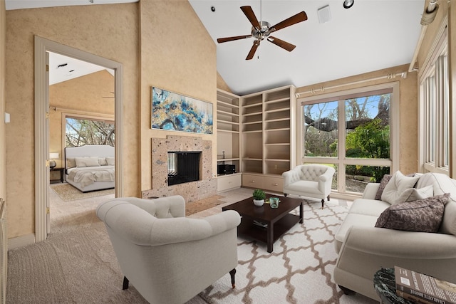 living room with ceiling fan, a tile fireplace, and high vaulted ceiling