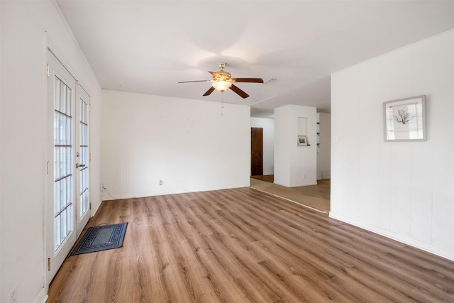 empty room featuring french doors, ceiling fan, and light hardwood / wood-style flooring