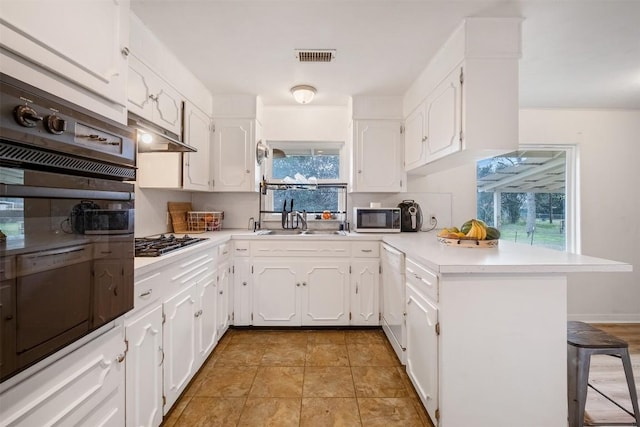 504 Marburger St, Smithville, TX 78957 - kitchen featuring a peninsula, black oven, a sink, a breakfast bar area, and stainless steel gas cooktop