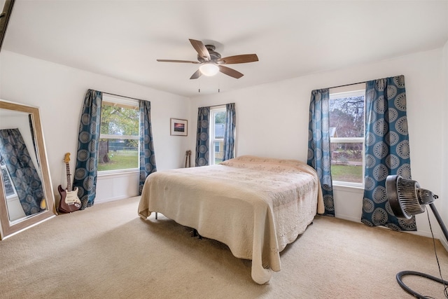 carpeted bedroom featuring multiple windows and ceiling fan