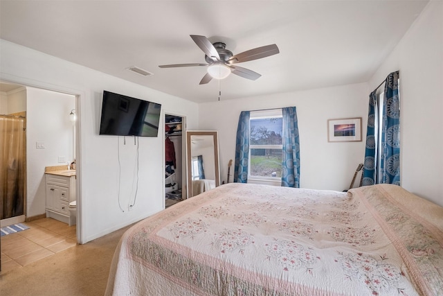 bedroom with ensuite bathroom, sink, light colored carpet, ceiling fan, and a closet