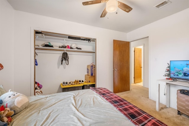 bedroom with light colored carpet, ceiling fan, and a closet