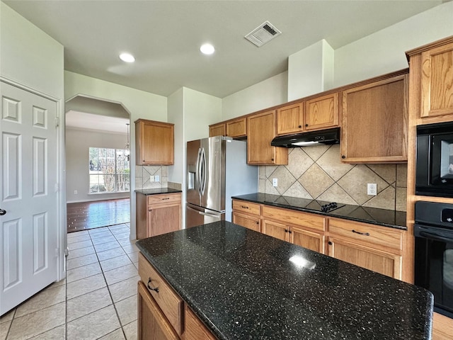 kitchen with light tile patterned floors, black appliances, decorative backsplash, a kitchen island, and dark stone countertops