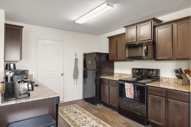 kitchen with dark hardwood / wood-style floors, black appliances, light stone countertops, dark brown cabinets, and a textured ceiling