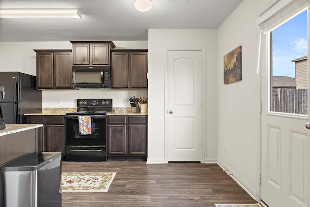 kitchen with dark brown cabinetry, light stone countertops, black appliances, and dark hardwood / wood-style floors