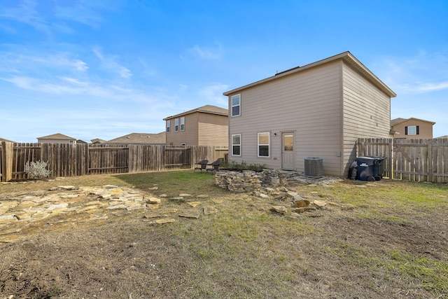 back of property with central AC and a lawn