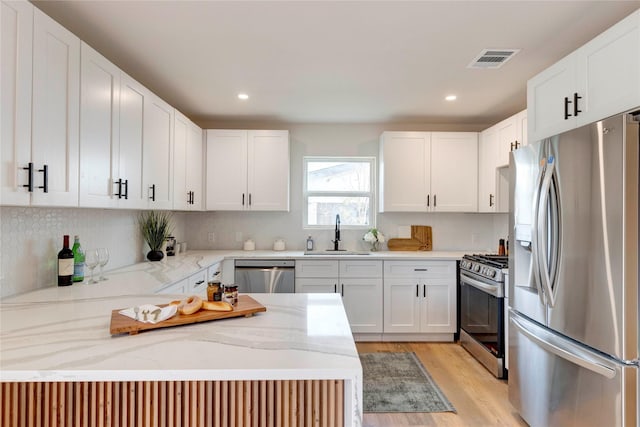 kitchen featuring light stone countertops, stainless steel appliances, light wood-type flooring, white cabinets, and sink