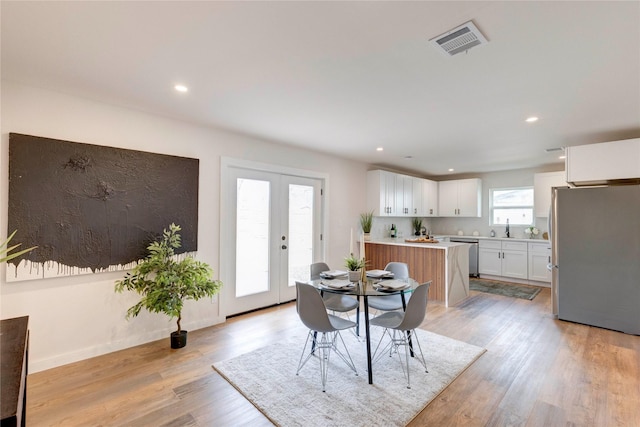 dining room featuring french doors, light hardwood / wood-style flooring, and sink