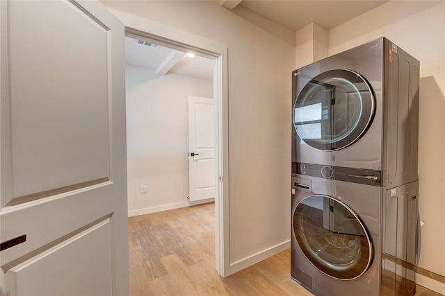 laundry area featuring stacked washer / drying machine and light wood-type flooring