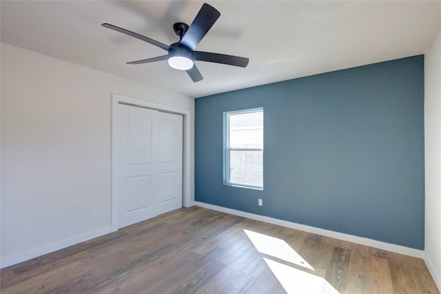 unfurnished bedroom featuring hardwood / wood-style floors, a closet, and ceiling fan