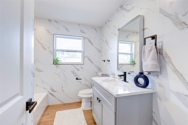 full bathroom featuring toilet, hardwood / wood-style flooring, a healthy amount of sunlight, and vanity