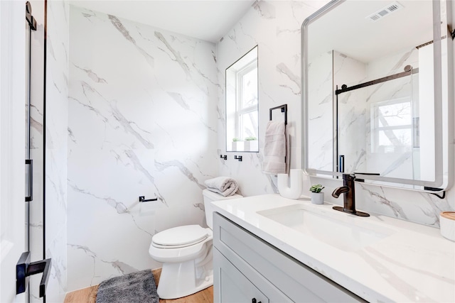 bathroom featuring toilet, walk in shower, and vanity