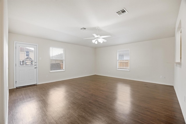 empty room with plenty of natural light, ceiling fan, and dark hardwood / wood-style floors