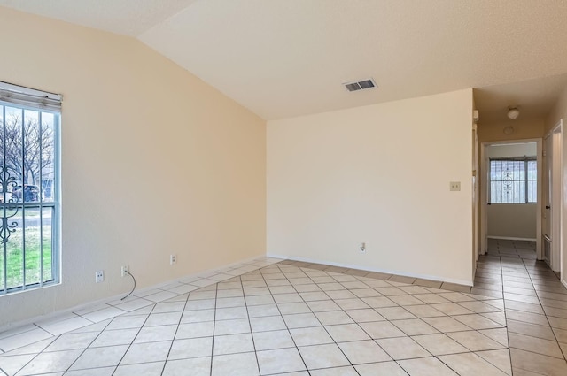 spare room featuring vaulted ceiling and light tile patterned floors