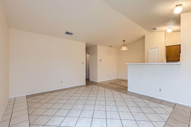 tiled spare room featuring a textured ceiling and vaulted ceiling