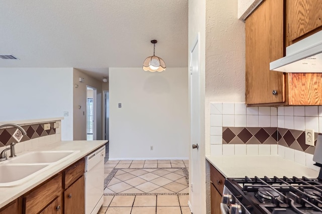 kitchen with hanging light fixtures, gas stove, white dishwasher, sink, and backsplash