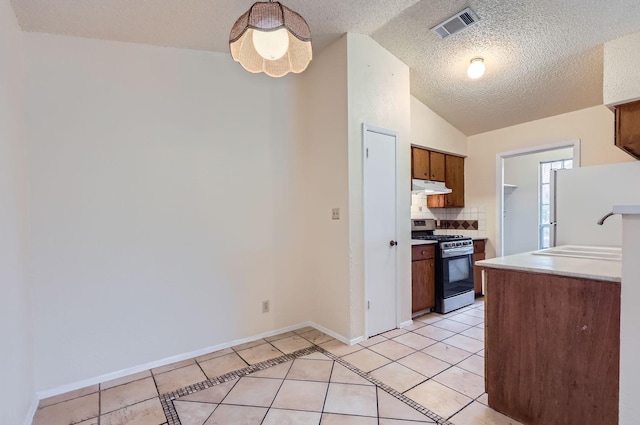 kitchen featuring vaulted ceiling, stainless steel range with gas cooktop, light tile patterned floors, tasteful backsplash, and sink