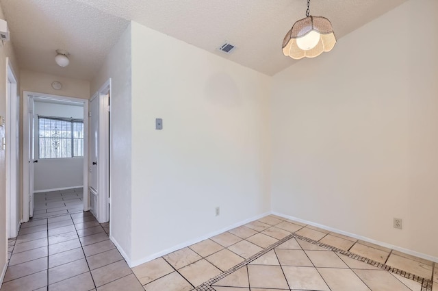 empty room with a textured ceiling and light tile patterned floors