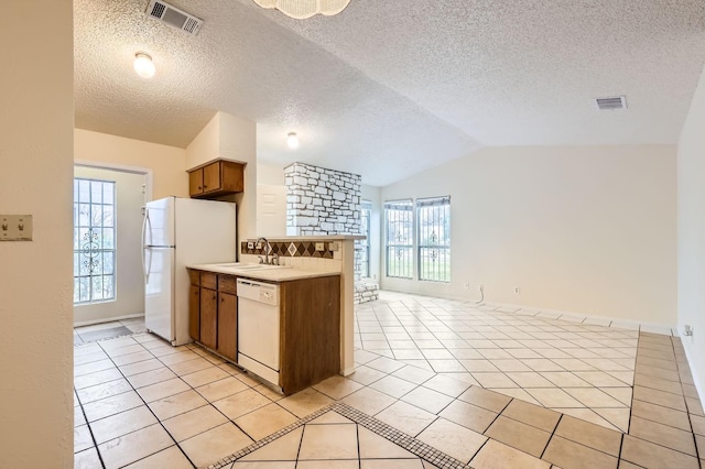 kitchen with lofted ceiling, light tile patterned floors, white appliances, and sink