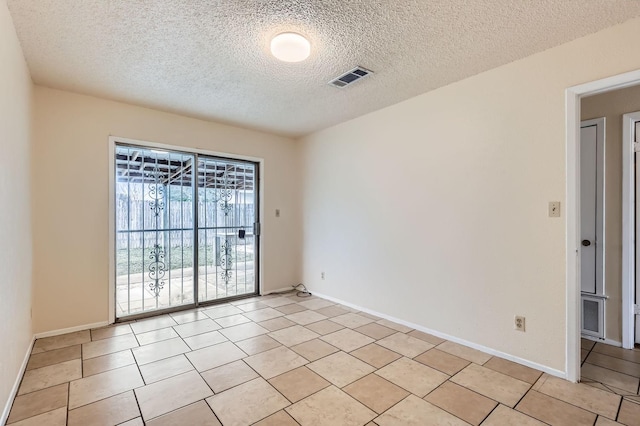 tiled empty room featuring a textured ceiling