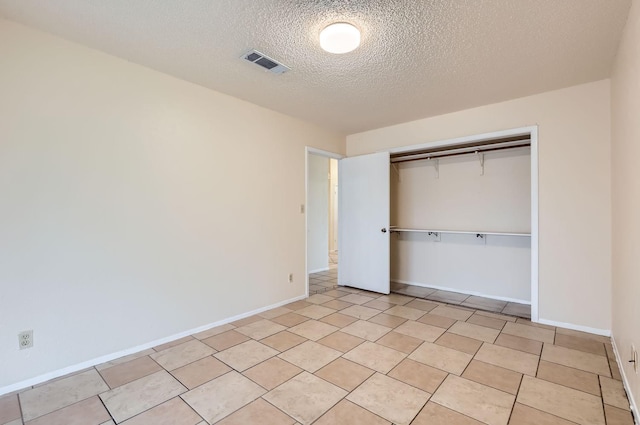 unfurnished bedroom featuring light tile patterned flooring, a closet, and a textured ceiling