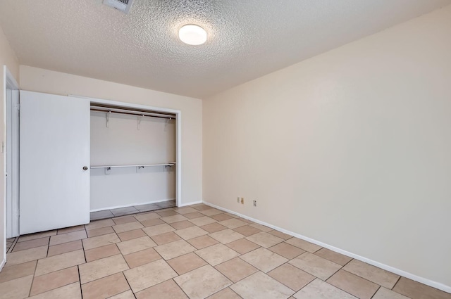 unfurnished bedroom with a textured ceiling, a closet, and light tile patterned floors