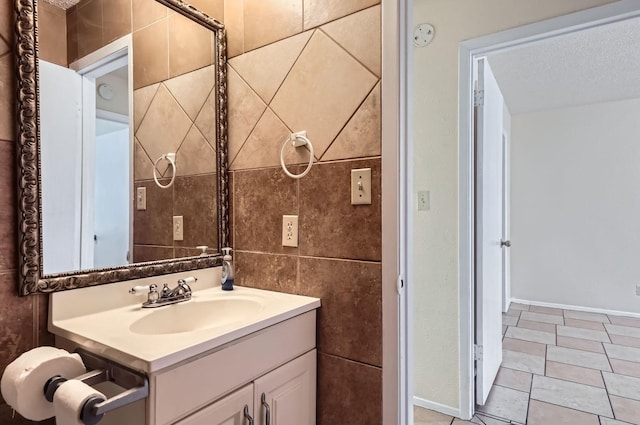 bathroom with tile patterned floors, vanity, tile walls, and a textured ceiling