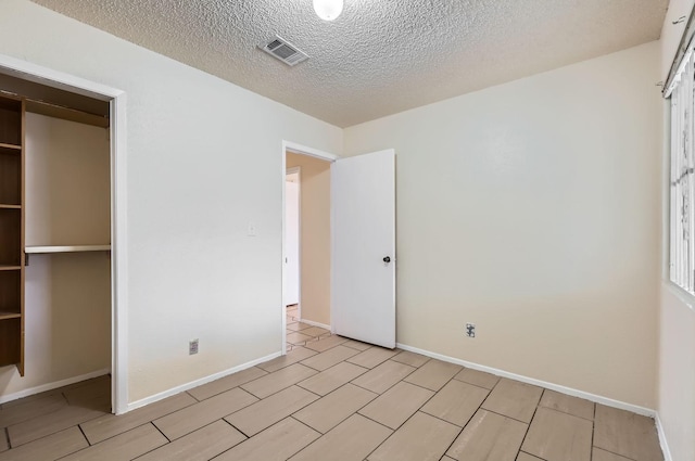 unfurnished bedroom with a textured ceiling and a closet