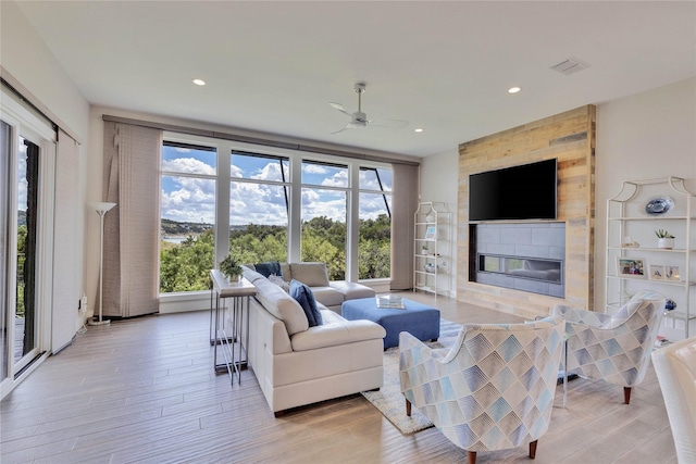 living room featuring ceiling fan, light wood-type flooring, and plenty of natural light