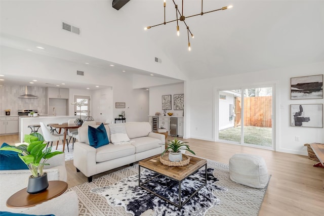 living room with a notable chandelier, light hardwood / wood-style flooring, and a high ceiling