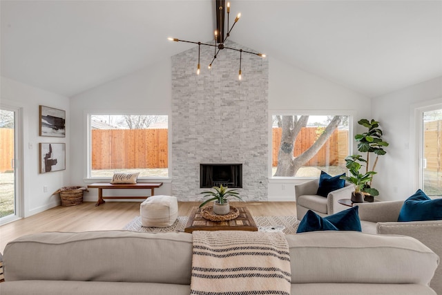 living room featuring wood-type flooring, a chandelier, vaulted ceiling, and a stone fireplace