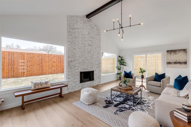 living room featuring beam ceiling, light hardwood / wood-style flooring, a healthy amount of sunlight, and a fireplace