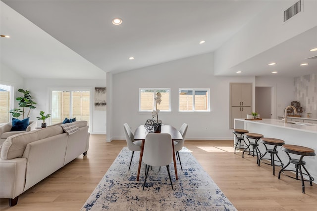 dining room featuring vaulted ceiling, light hardwood / wood-style floors, and sink