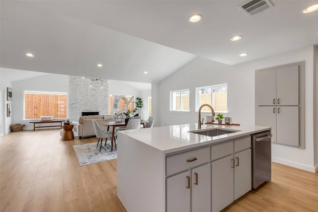 kitchen featuring lofted ceiling, a center island with sink, light hardwood / wood-style flooring, and sink