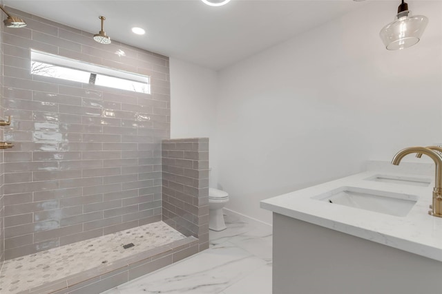 bathroom featuring toilet, tiled shower, and vanity