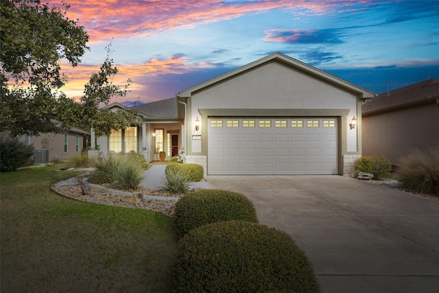 ranch-style home with a lawn, central AC unit, and a garage