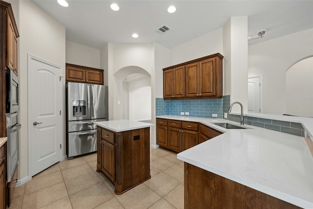 kitchen with appliances with stainless steel finishes, sink, light tile patterned flooring, and a kitchen island