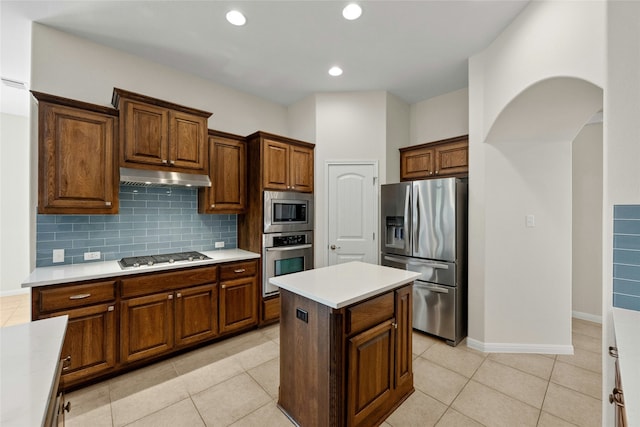 kitchen with stainless steel appliances, a kitchen island, light tile patterned flooring, and tasteful backsplash