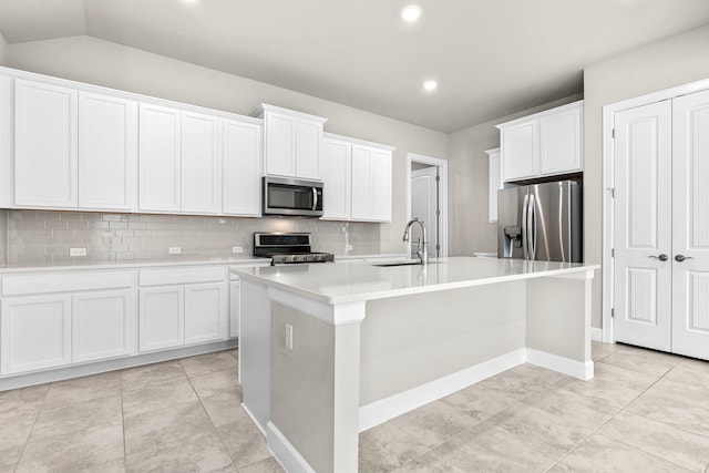 kitchen with appliances with stainless steel finishes, white cabinets, sink, and a center island with sink