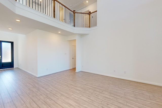 spare room with light hardwood / wood-style flooring and a towering ceiling