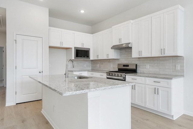 kitchen with sink, stainless steel appliances, light stone countertops, a kitchen island with sink, and white cabinets