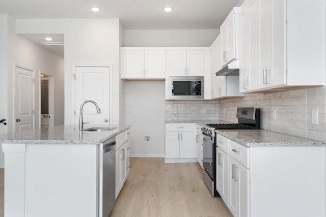 kitchen with stainless steel appliances, light stone countertops, sink, and white cabinets