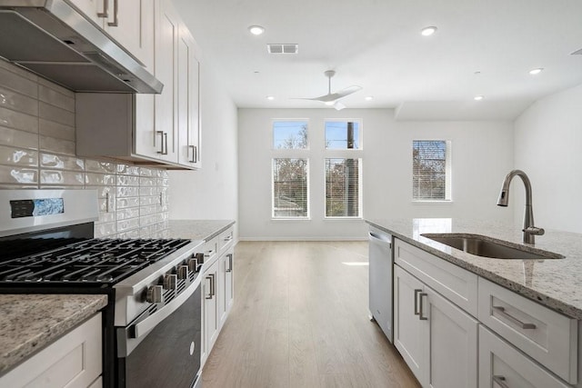 kitchen with sink, backsplash, stainless steel appliances, light stone counters, and white cabinets