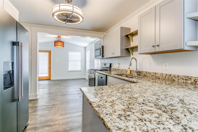 kitchen with stainless steel appliances, sink, light hardwood / wood-style flooring, light stone countertops, and pendant lighting